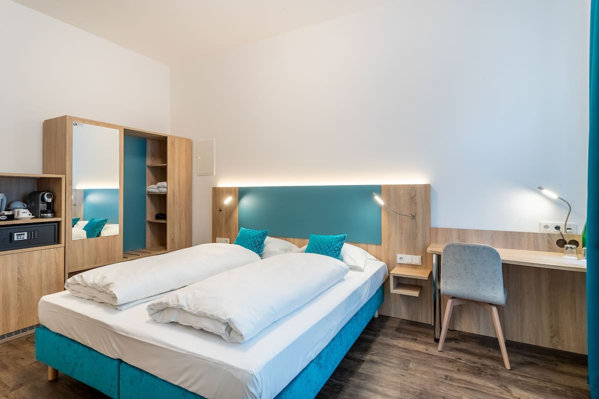 A modern hotel room with a bed, a desk, and a chair.