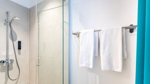 A modern bathroom with a glass shower enclosure, a towel rack with two white towels, and a teal accent wall. - DaunTown Rooms - Self Check-In (Vienna)