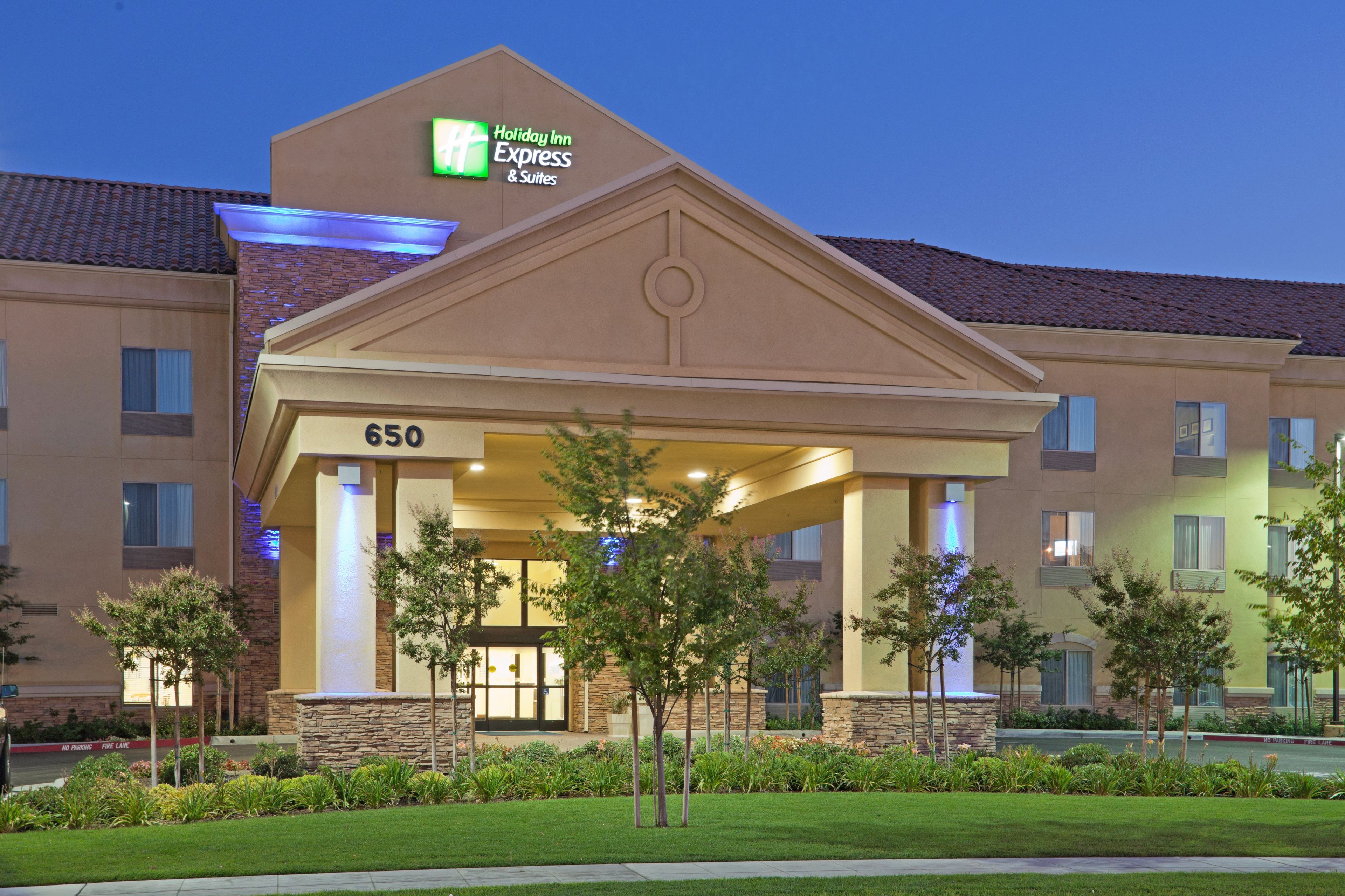 Edificio de Holiday Inn Express & Suites con entrada cubierta, número 650, y un jardín delantero ajardinado con árboles.