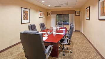 A conference room with a long table, six chairs, and framed artwork on the walls.