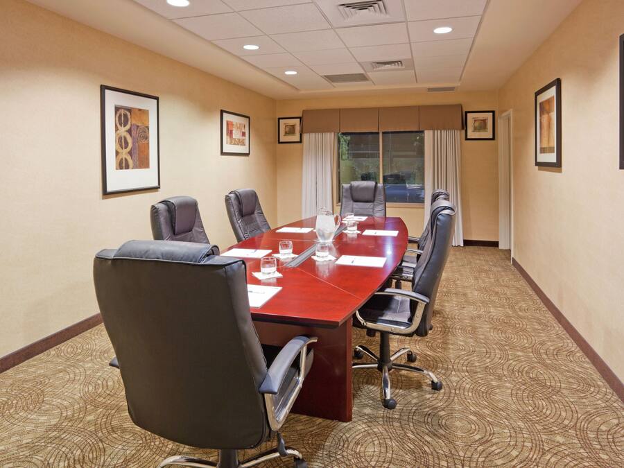 A conference room with a long table, six chairs, and framed artwork on the walls.