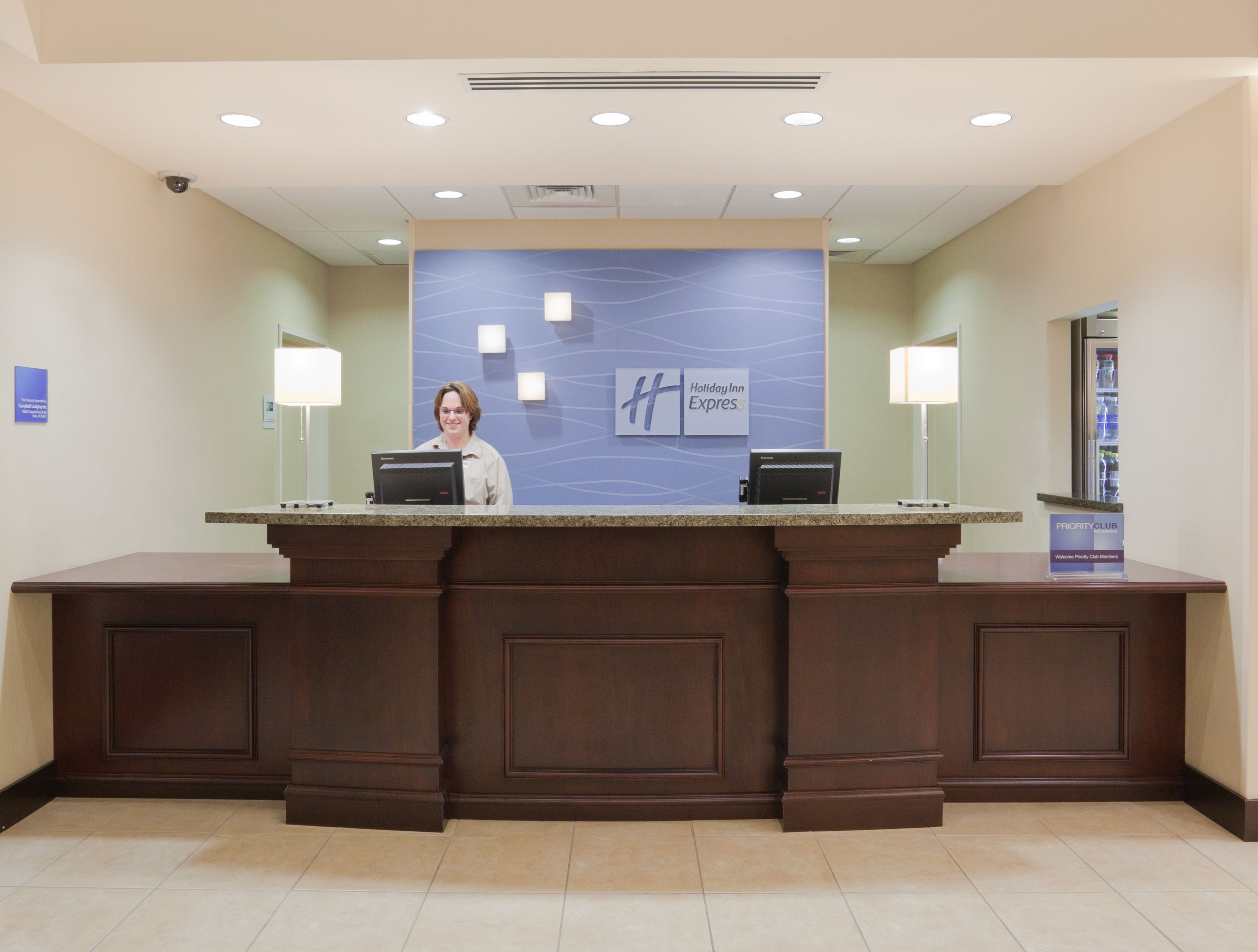 A reception desk with a Holiday Inn Express sign, a computer, and a Priority Club sign.