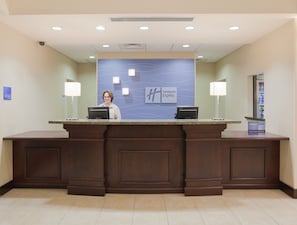 Un mostrador de recepción con el letrero de Holiday Inn Express, una computadora y el logo de Priority Club.