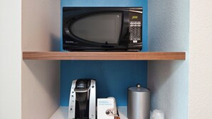 A microwave on a shelf, a Keurig coffee maker, a glass, and a stainless steel container. - Holiday Inn Express & Suites Clovis-Fresno Area by IHG (Clovis)