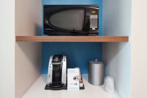 A microwave on a shelf, a Keurig coffee maker, a glass, and a stainless steel container. - Holiday Inn Express & Suites Clovis-Fresno Area by IHG (Clovis)