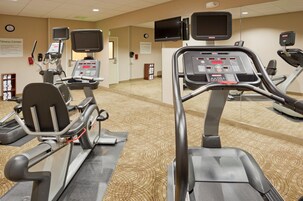 Un gimnasio con cintas de correr, bicicletas estáticas y equipo de ejercicio.