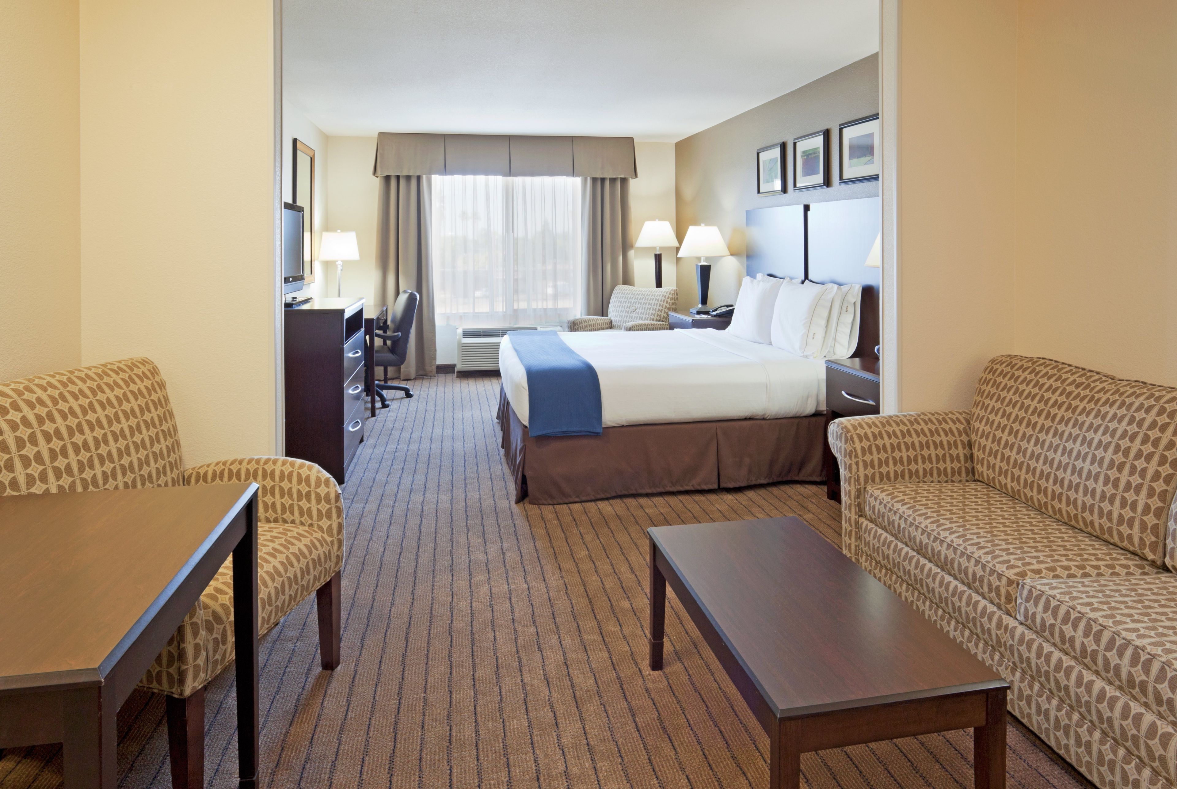 A hotel room with a bed, two sofas, a desk, and a TV.