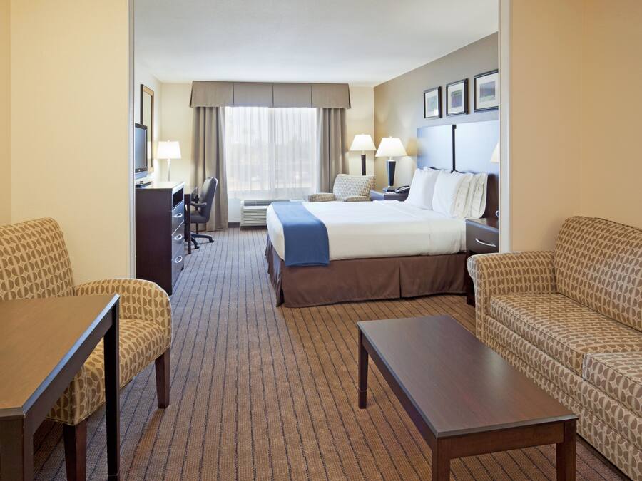 A hotel room with a bed, two sofas, a desk, and a TV.