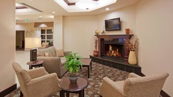 Un hall con chimenea, zona de estar y televisor montado en la pared.