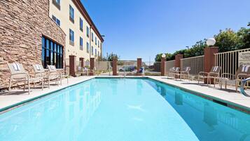 A swimming pool with lounge chairs and a stone building in the background.