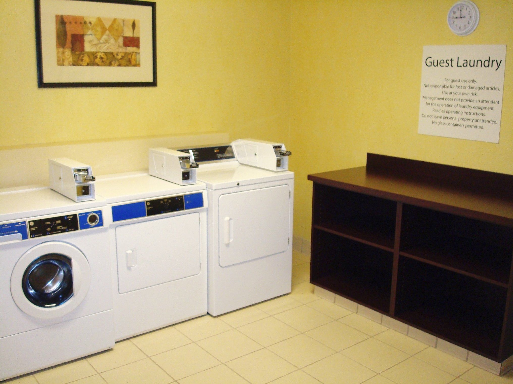 A guest laundry area with a washing machine, dryer, and a sign with laundry instructions.