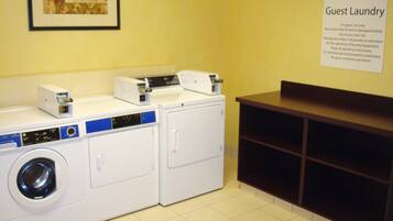 A guest laundry area with a washing machine, dryer, and a sign with laundry instructions.
