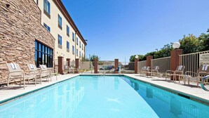 A swimming pool with lounge chairs, a stone building, and a fence. - Holiday Inn Express & Suites Clovis-Fresno Area by IHG (Clovis)