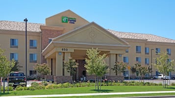 A Holiday Inn Express & Suites building with a classic architectural design, featuring a prominent entrance and a numbered address.