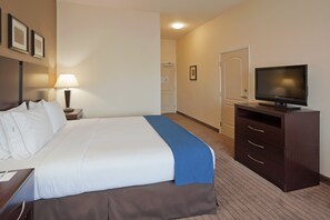 Una habitación de hotel con cama, escritorio, televisor y puerta.