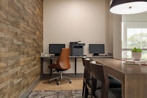 A modern office space with two desks, a brown leather chair, a potted plant, and a large window. - Candlewood Suites Springfield North by IHG (Springfield)