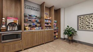A kitchenette with a coffee machine, a microwave, and a variety of packaged goods on shelves. - Candlewood Suites Springfield North by IHG (Springfield)
