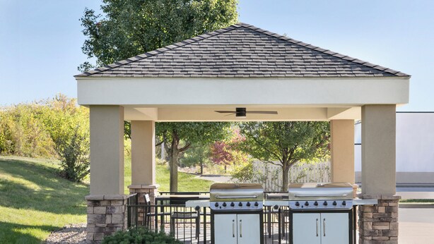 A covered outdoor grill area with a gazebo structure, stone pillars, and a small bush. - Candlewood Suites Springfield North by IHG (Springfield)