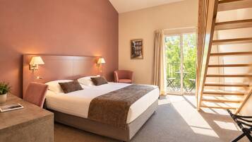 A hotel room with a bed, bedside lamps, a chair, a desk, a balcony with a table, and a view of greenery.