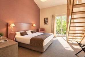 A hotel room with a bed, bedside lamps, a chair, a desk, a balcony with a table, and a view of greenery. - Hotel Mercure Aix en Provence Sainte Victoire (Chateauneuf-le-Rouge)