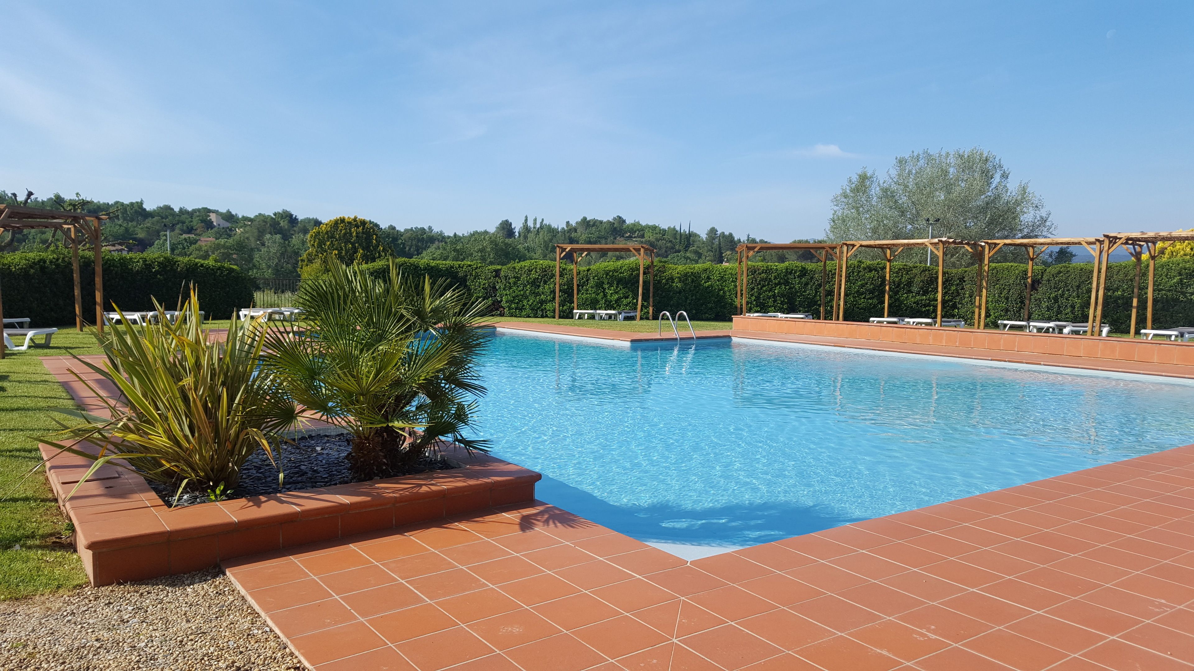 Una piscina al aire libre, sillones reclinables de piscina