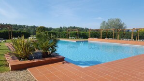 A swimming pool with a tiled deck, surrounded by greenery and a pergola structure. - Hotel Mercure Aix en Provence Sainte Victoire (Chateauneuf-le-Rouge)