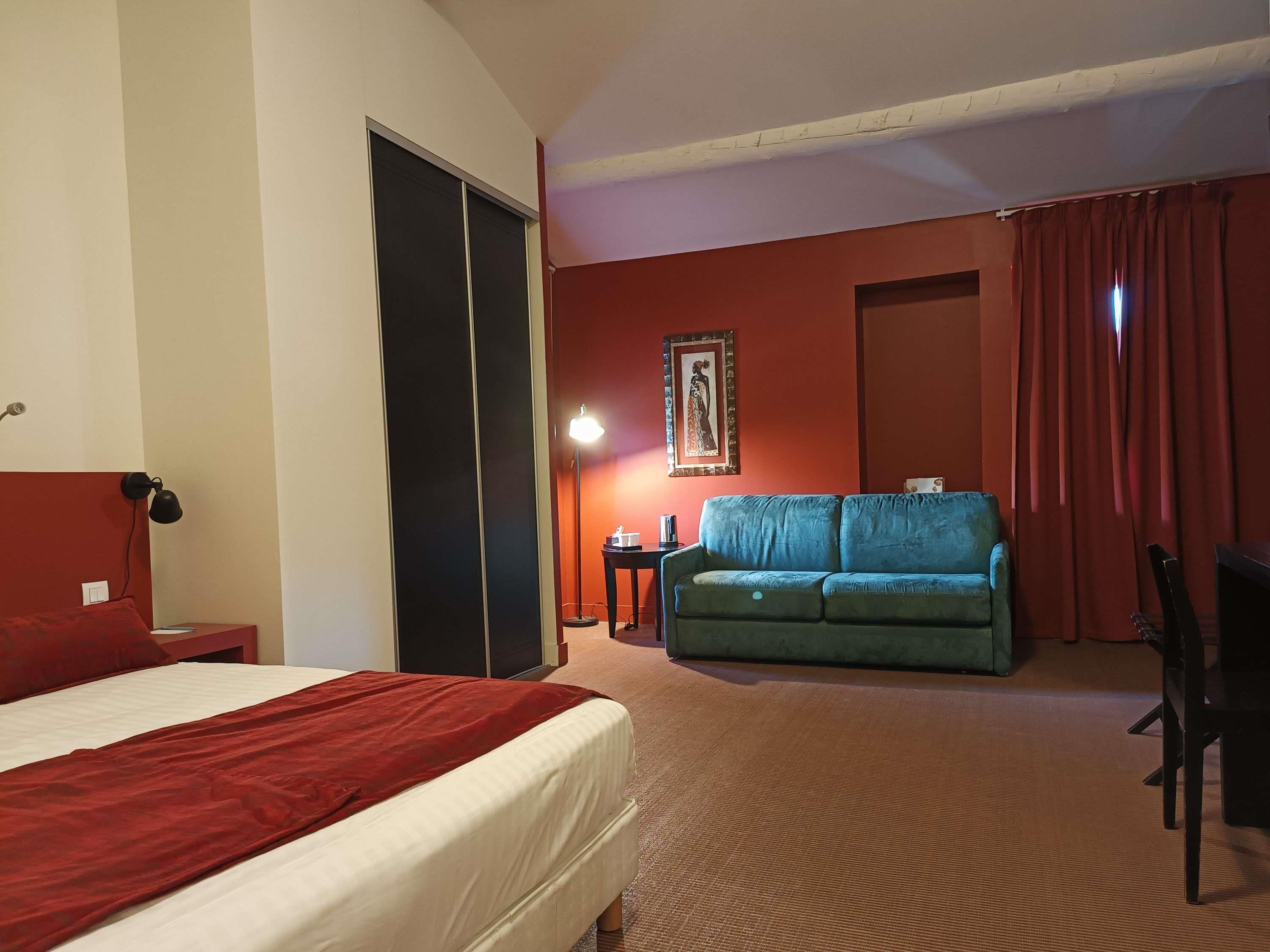 Una habitación de hotel con cama, sofá, escritorio, silla y lámpara.