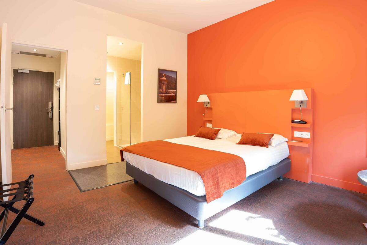 Une chambre d’hôtel avec un lit, une douche, une porte et une petite table.