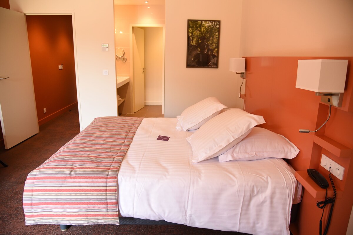 Quarto de hotel com uma cama, um telefone e uma pintura na parede.