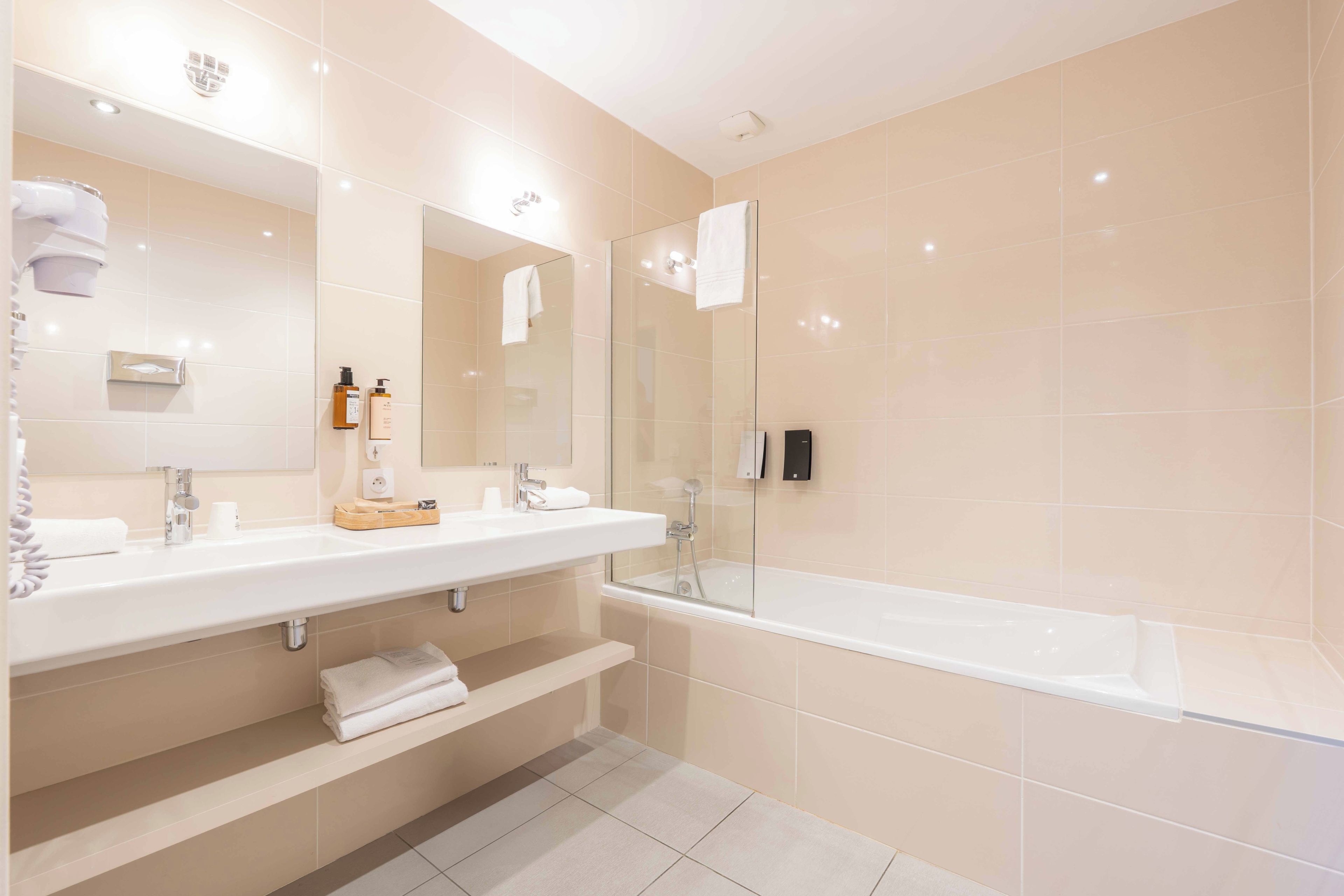 A modern bathroom with two sinks, a bathtub, and a glass shower enclosure.