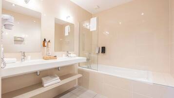 A modern bathroom with two sinks, a bathtub, and a glass shower enclosure.