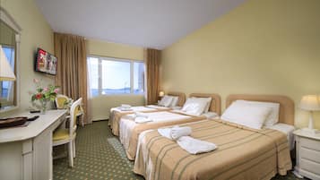 Ein Hotelzimmer mit zwei Betten, einem Schreibtisch, einem Stuhl und einem Fenster mit Blick.