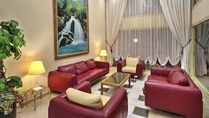 Una sala de estar con un sofá rojo, una mesa de centro de cristal y un cuadro de una cascada en la pared.