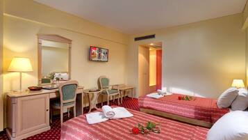 Habitación de hotel con dos camas, un escritorio, una silla, un espejo y una mesita.
