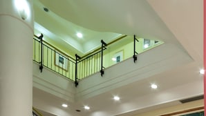 Un interior de varios niveles con una escalera, un mural grande y un techo luminoso.