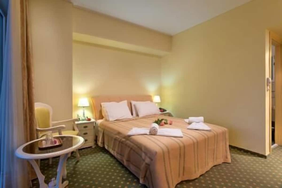 Une chambre d’hôtel comprenant un lit, deux tables de chevet, une petite table ronde et une chaise.