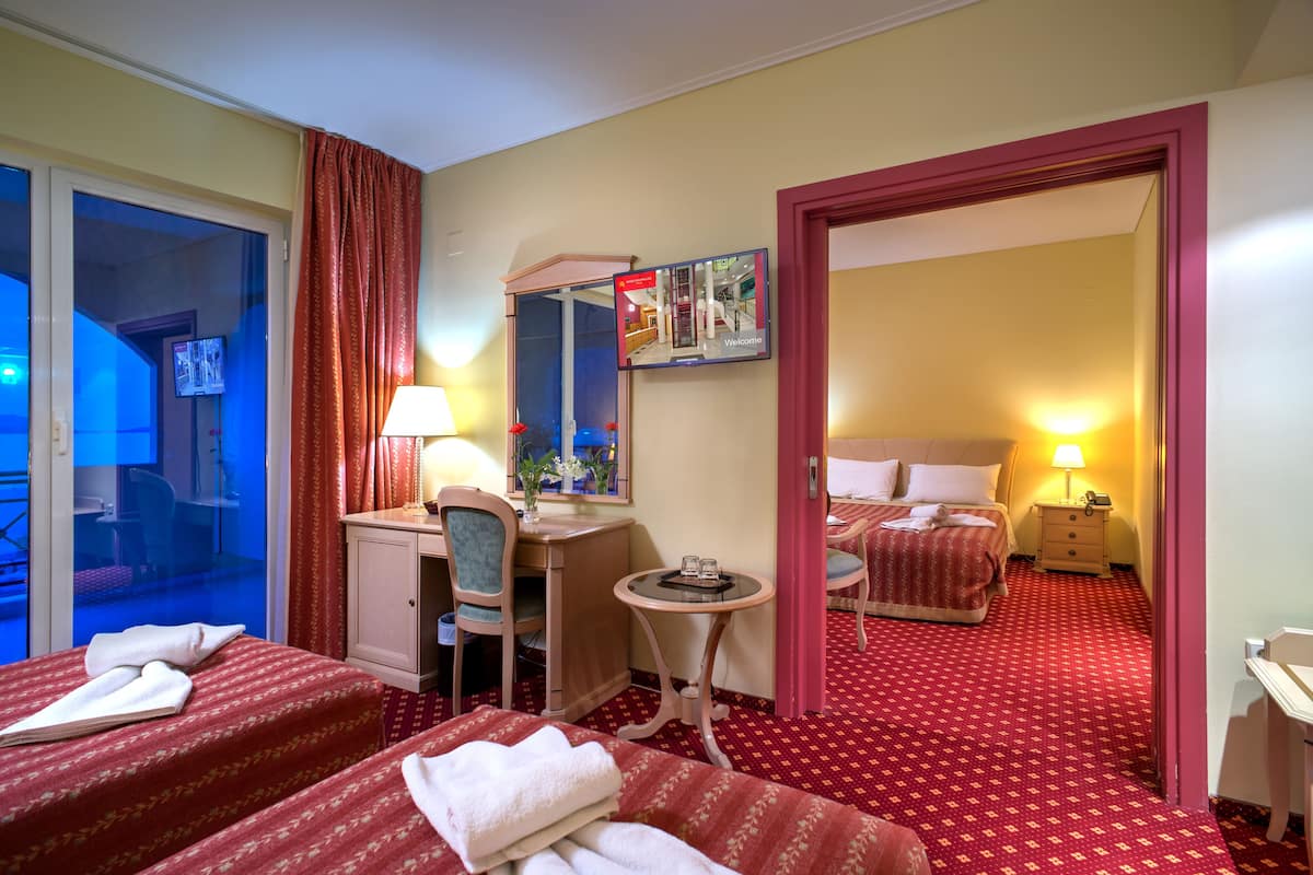 Une chambre d’hôtel avec deux lits, un bureau, une chaise, une petite table, une lampe et un miroir.