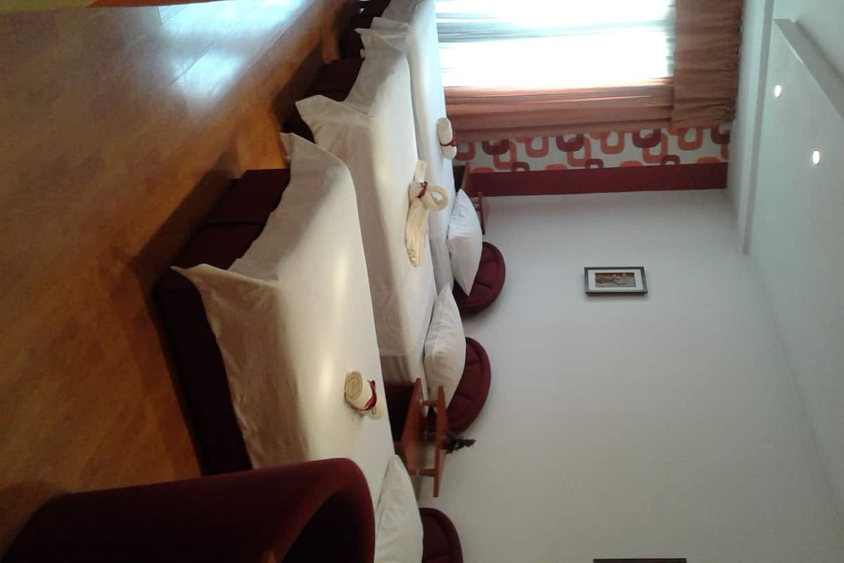 Habitación de hotel con un banco de madera, asientos acolchados de color rojo, una mesita y un cuadro en la pared.