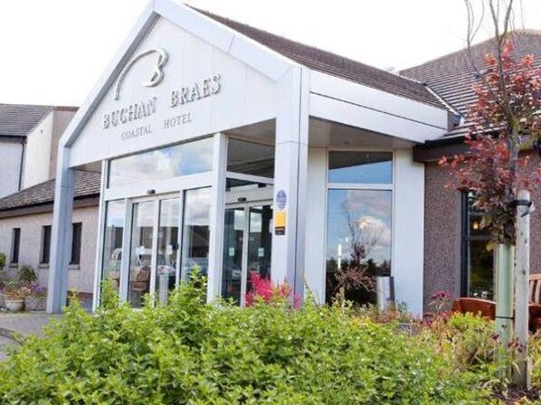 A coastal hotel with a prominent sign, large windows, and a well-maintained garden. - Buchan Braes Hotel (Peterhead)