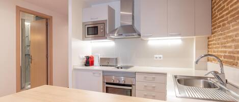 A modern kitchen with white cabinets, stainless steel appliances, a built-in oven, and a sink.