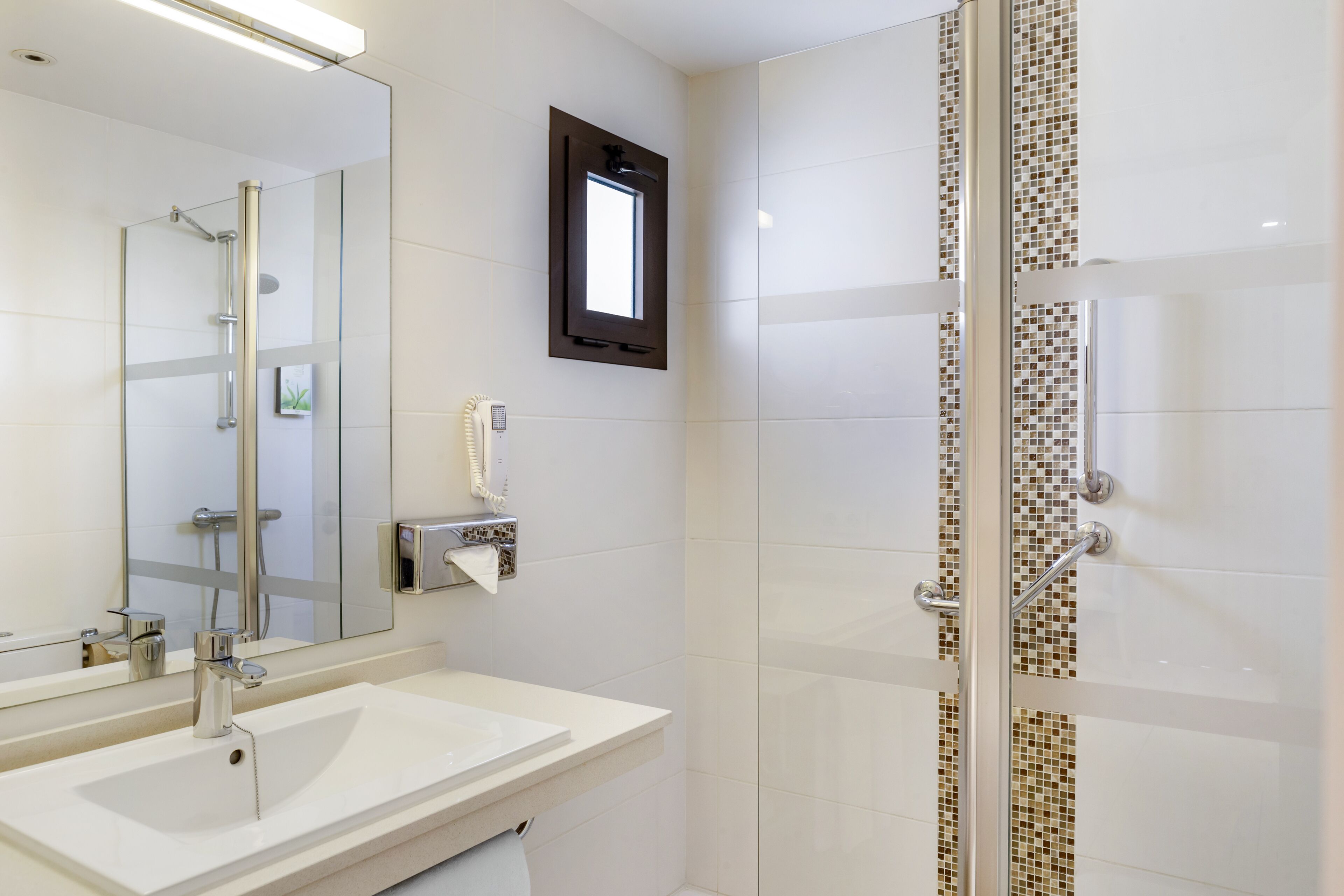 A modern bathroom with a glass shower enclosure, a large mirror, and a white sink.