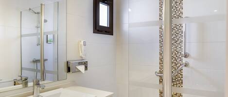 A modern bathroom with a glass shower enclosure, a large mirror, and a white sink.