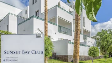 A white building with balconies and a sign reading "Sunset Bay Club."