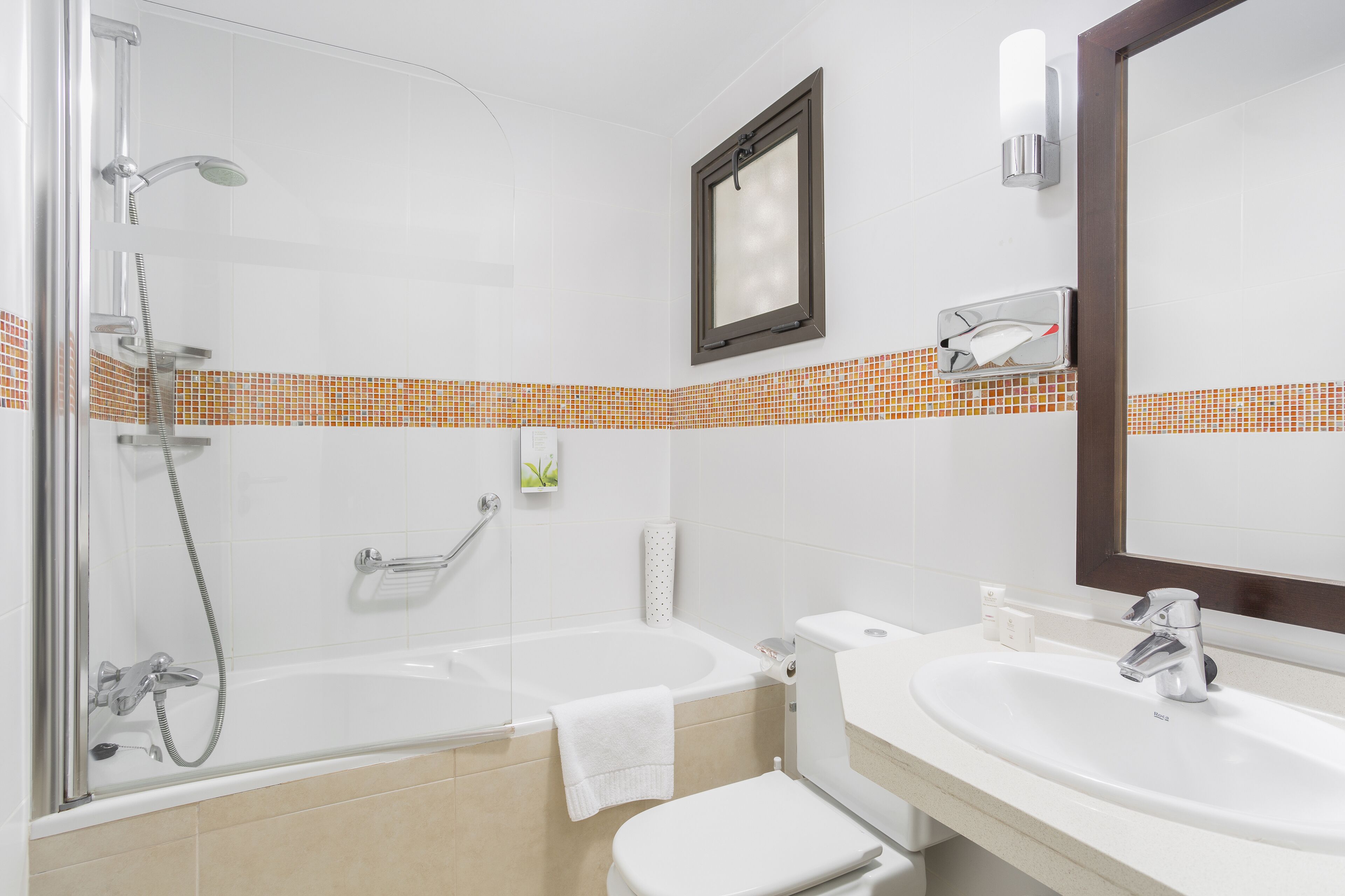 Un baño moderno con ducha de vidrio, una bañera, inodoro y lavamanos con espejo.
