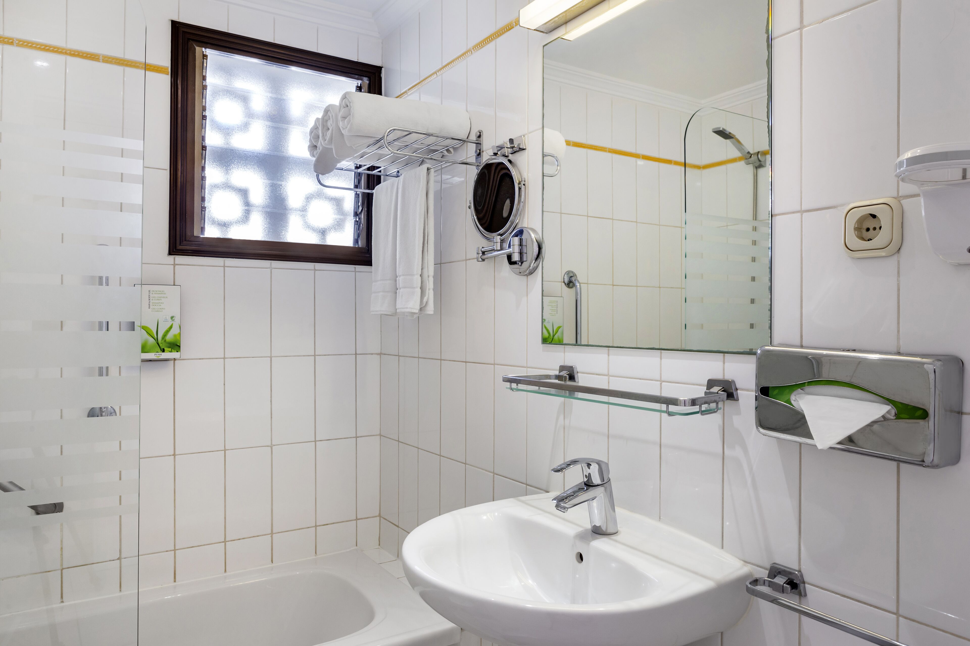 Un bagno moderno con un lavandino bianco, cabina doccia in vetro, porta asciugamani e uno specchio.