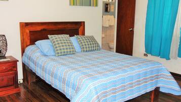 Una cama bien hecha con colcha a rayas, cabecera de madera y dos almohadas.