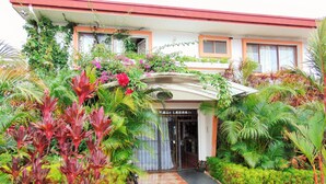 A building with a checkered pathway leading to a gated entrance, surrounded by lush greenery and various plants. - Casa Lima Bed & Breakfast (San José)