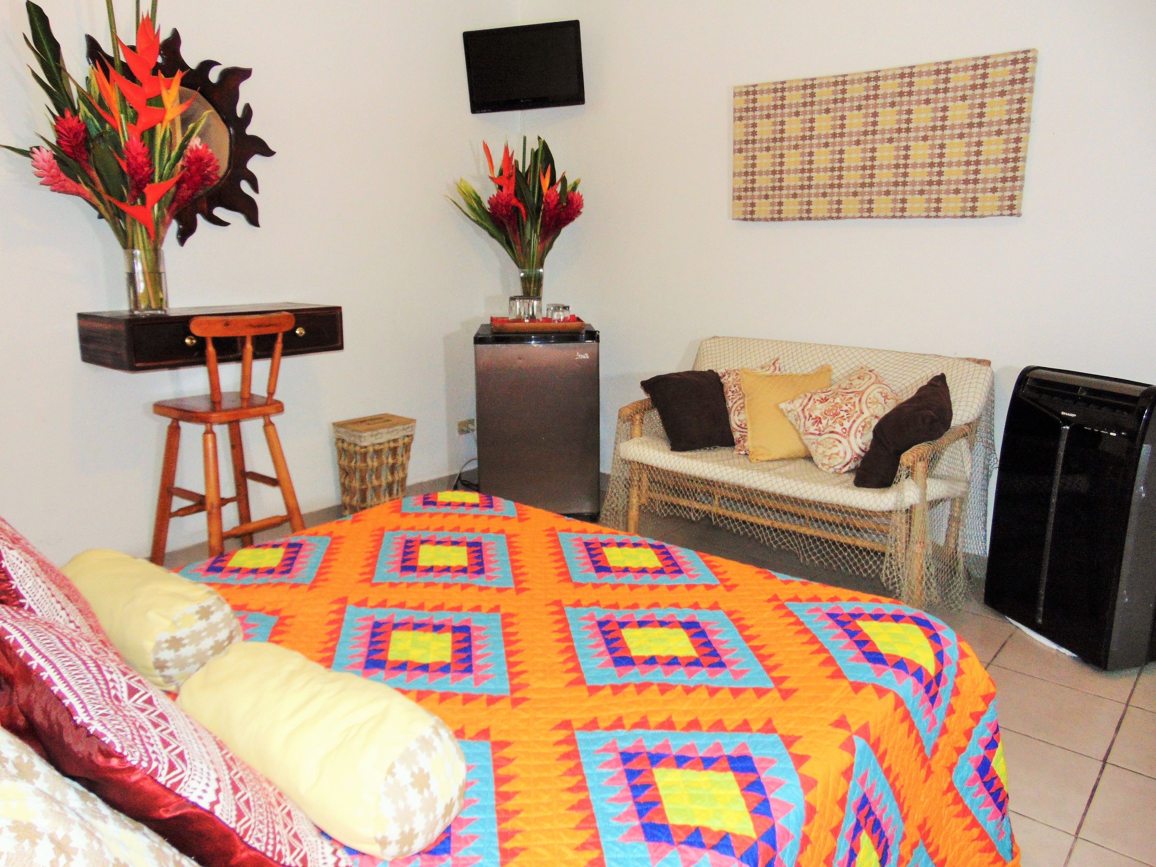 A room with a bed, a chair, a sofa, a TV, and a refrigerator.