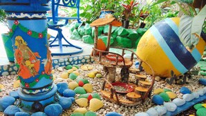 A colorful garden with a statue, a bird bath, and a large decorative sphere. - Casa Lima Bed & Breakfast (San José)