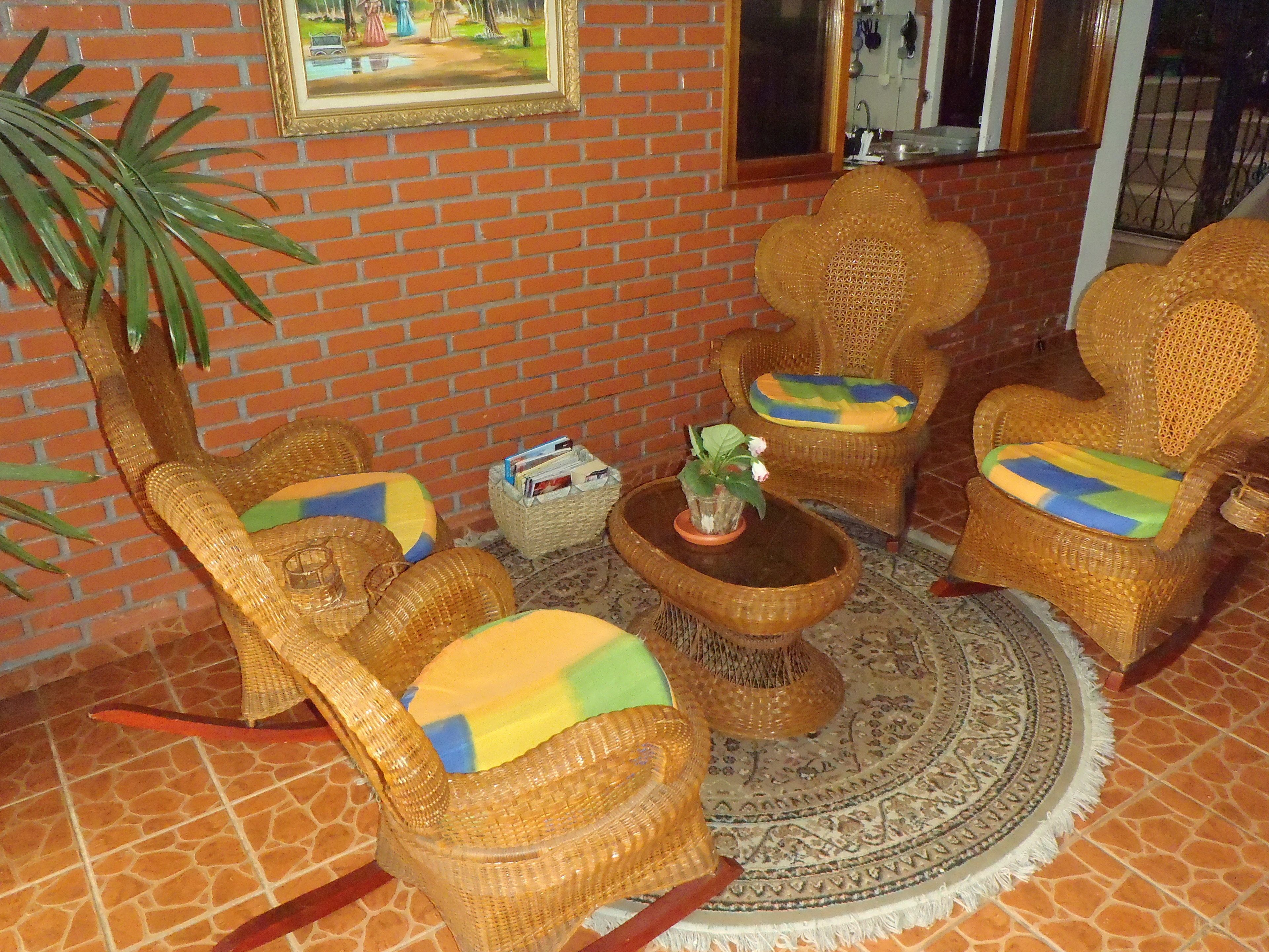 A room with wicker furniture, a round coffee table, and a potted plant.